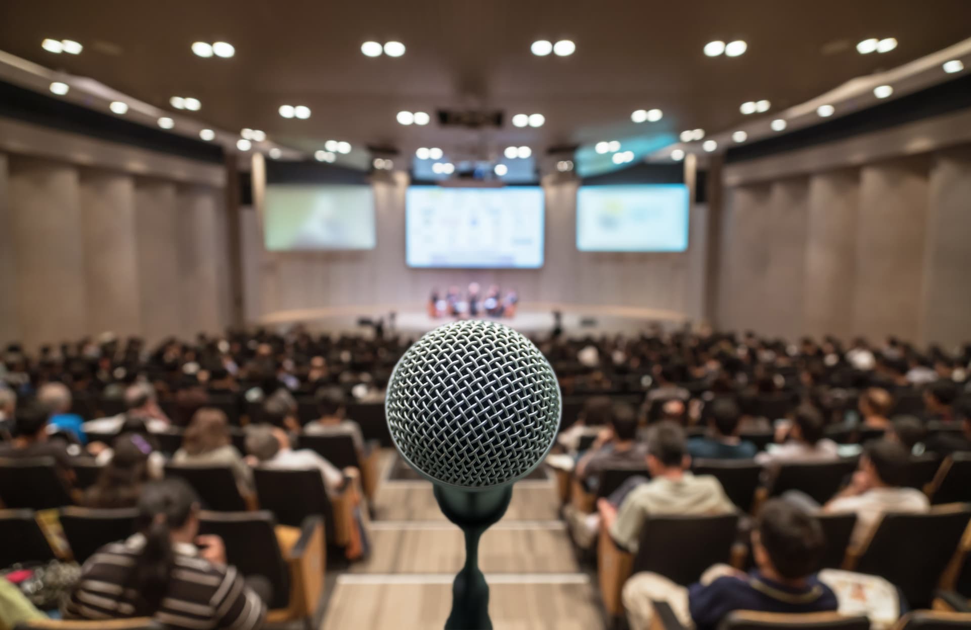 Microphone in sharp focus before a seated conference audience
